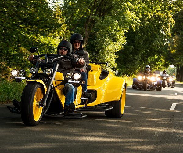 Gelbes rewaco Trike mit Fahrer und Beifahrerin in einer Gruppe