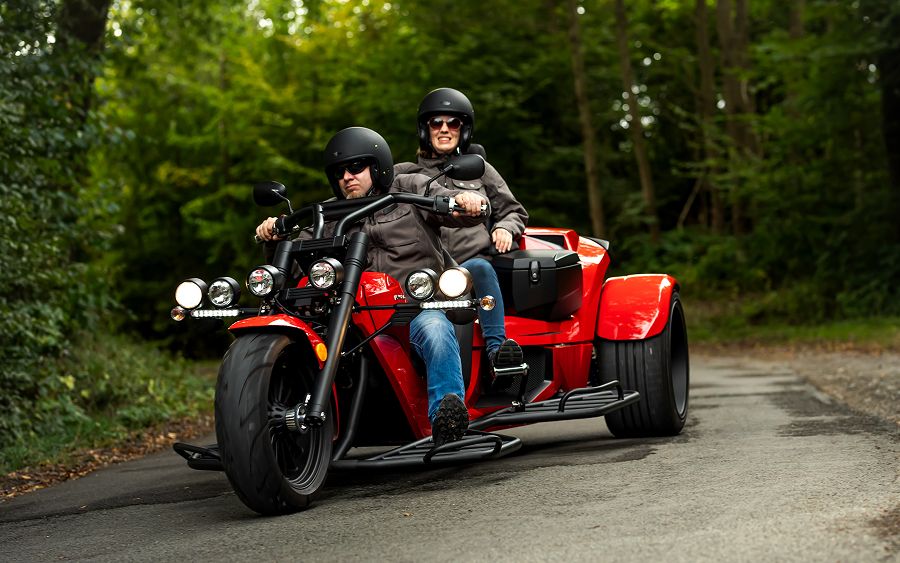 Fahrer mit Beifahrerin, beide mit Helm, auf einem roten rewaco Trike